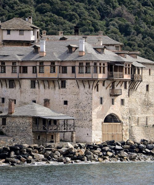 A historic stone monastery by the sea surrounded by lush greenery, capturing classic architecture.